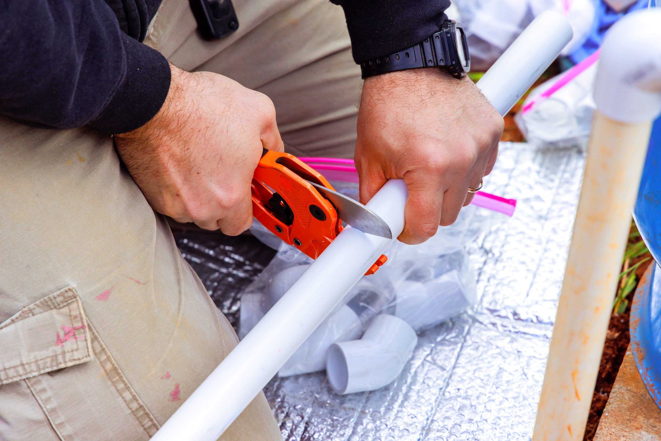hands carefully cutting white pvc pipe with a tool 2025 03 27 05 01 26 utc scaled